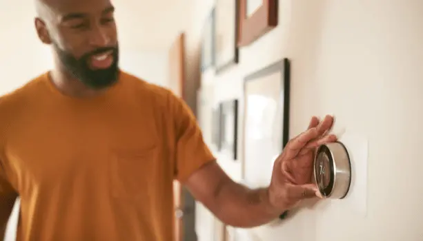 man adjusting smart thermostat